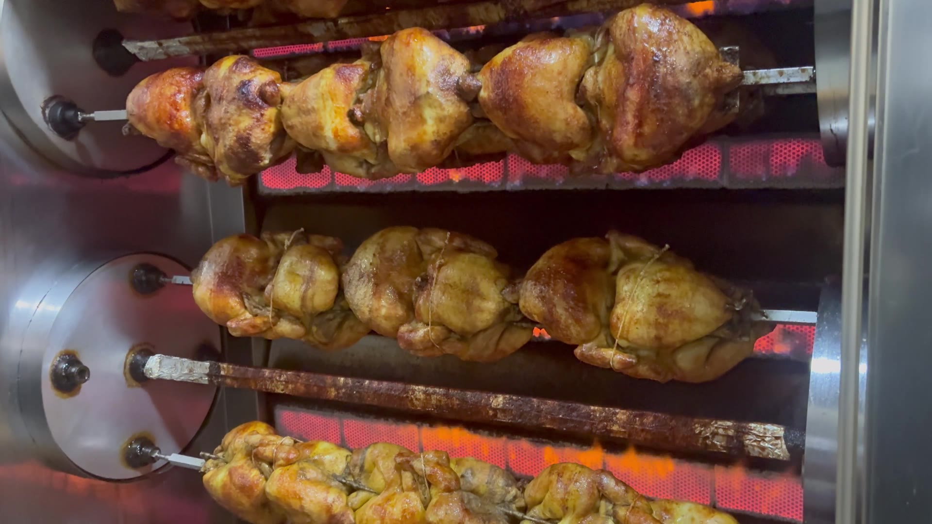Pollos dorándose al fuego vivo en el asador tradicional de Rostisseria MARFA en Ripollet
